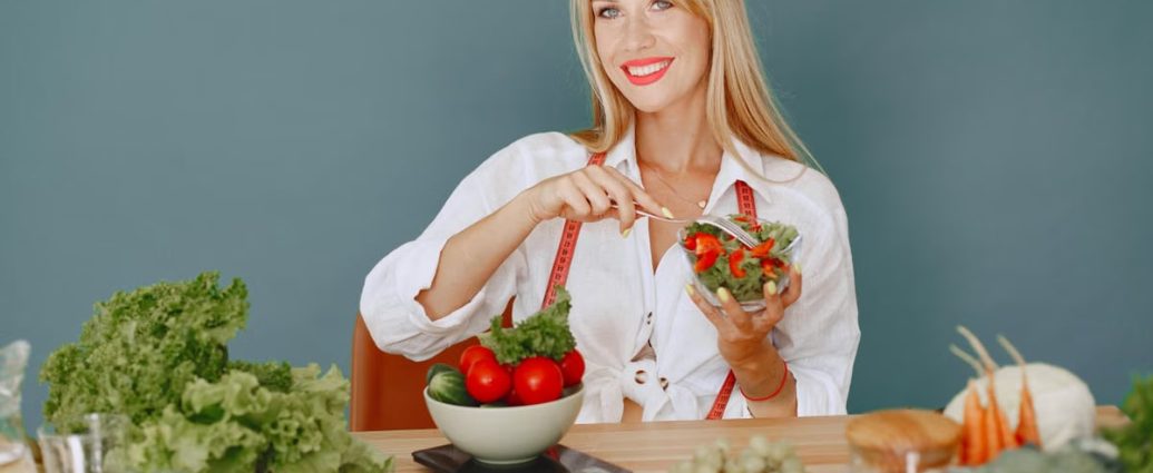 Blonde woman enjoying a fresh salad surrounded by vegetables, promoting healthy eating.