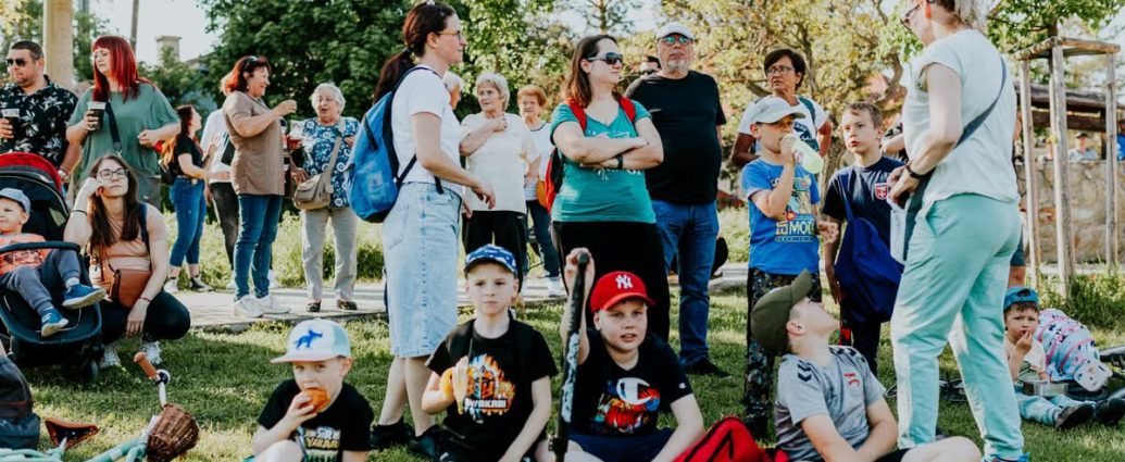 A diverse group of families and children enjoying an outdoor event on a sunny day in a park setting.