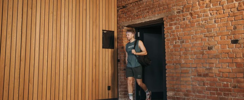 A sporty man leaving a brick-walled sports hall, embodying active lifestyle and fitness.