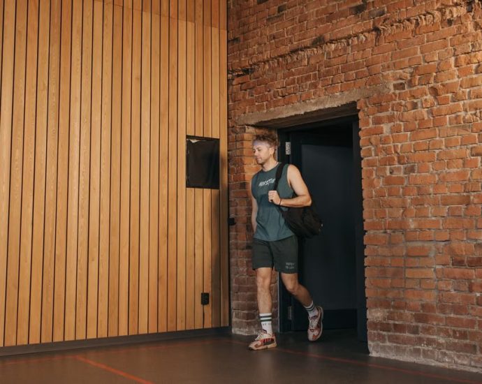 A sporty man leaving a brick-walled sports hall, embodying active lifestyle and fitness.